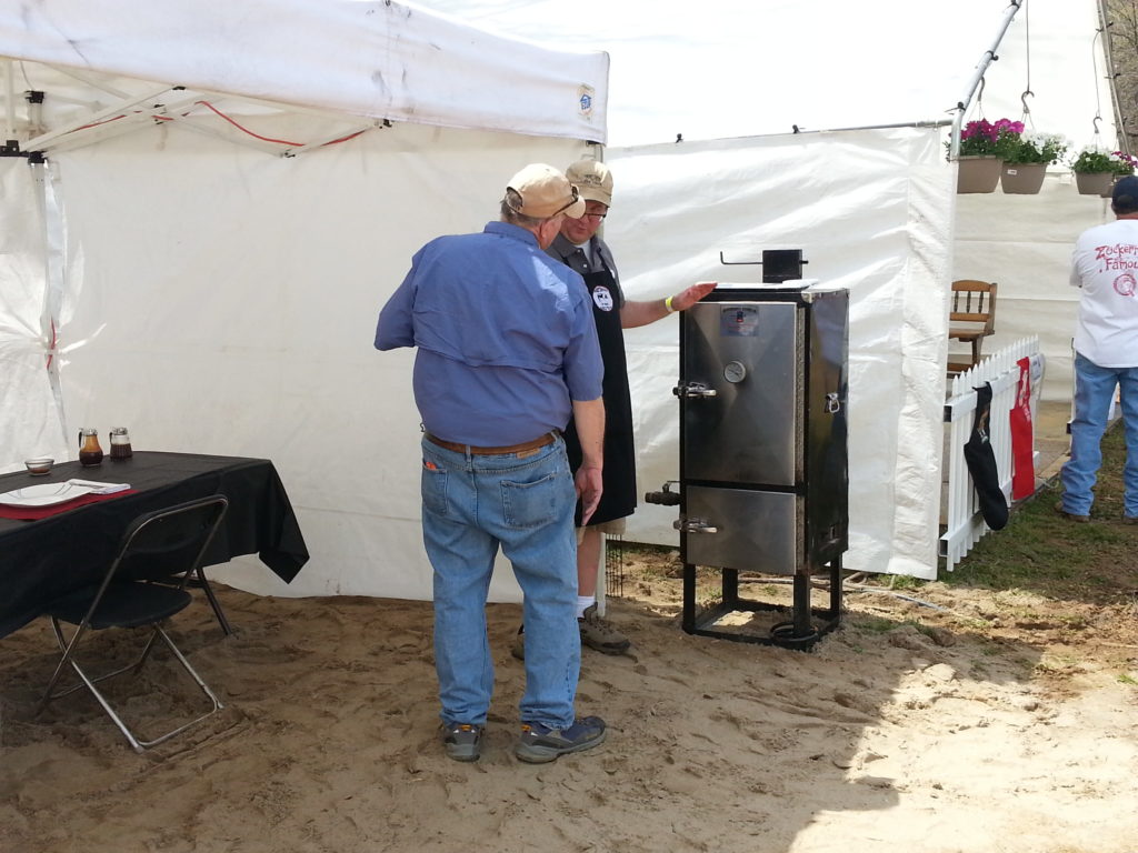 Sweet Swine O' Mine's Dr. Richard Lackie presenting on-site ribs to a judge in Atoka, TN. Inventory: Backwoods Smoker, Pop-up tent, table, chair, and plastic table cloth. That is IT (mostly). Notice the team next door has a floor, fence on the front, and plants hanging. It's nice to have, but we took 1st place in ribs without it.