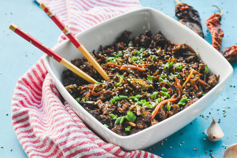 A bowl of egg roll in a bowl with two chopsticks sticking out.