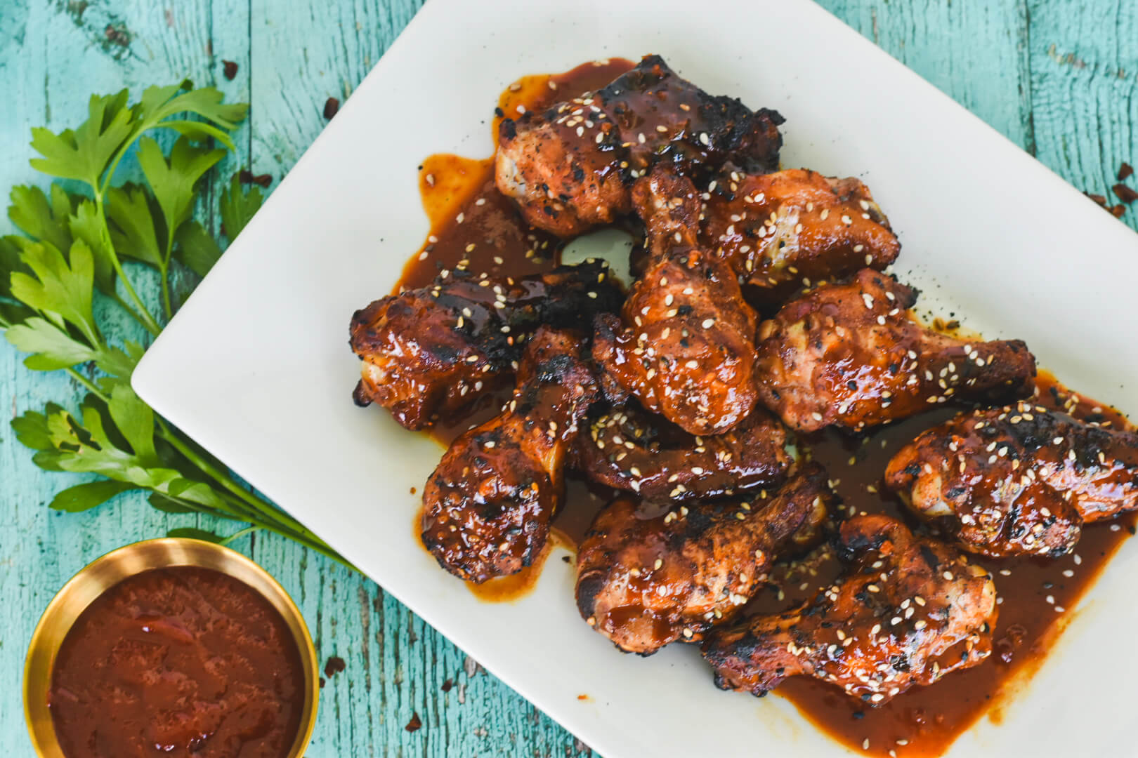 A plate of Korean wings tossed with gochujang sauce topped with sesame seeds.