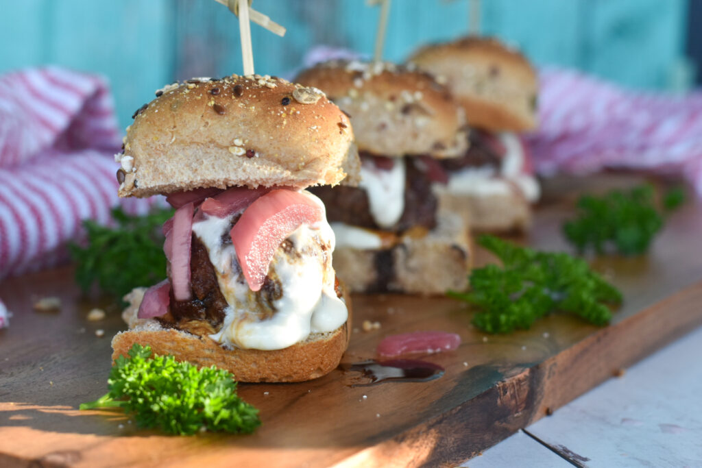Three lamb sliders with whipped feta, pickled onions, and pomegranate molasses.